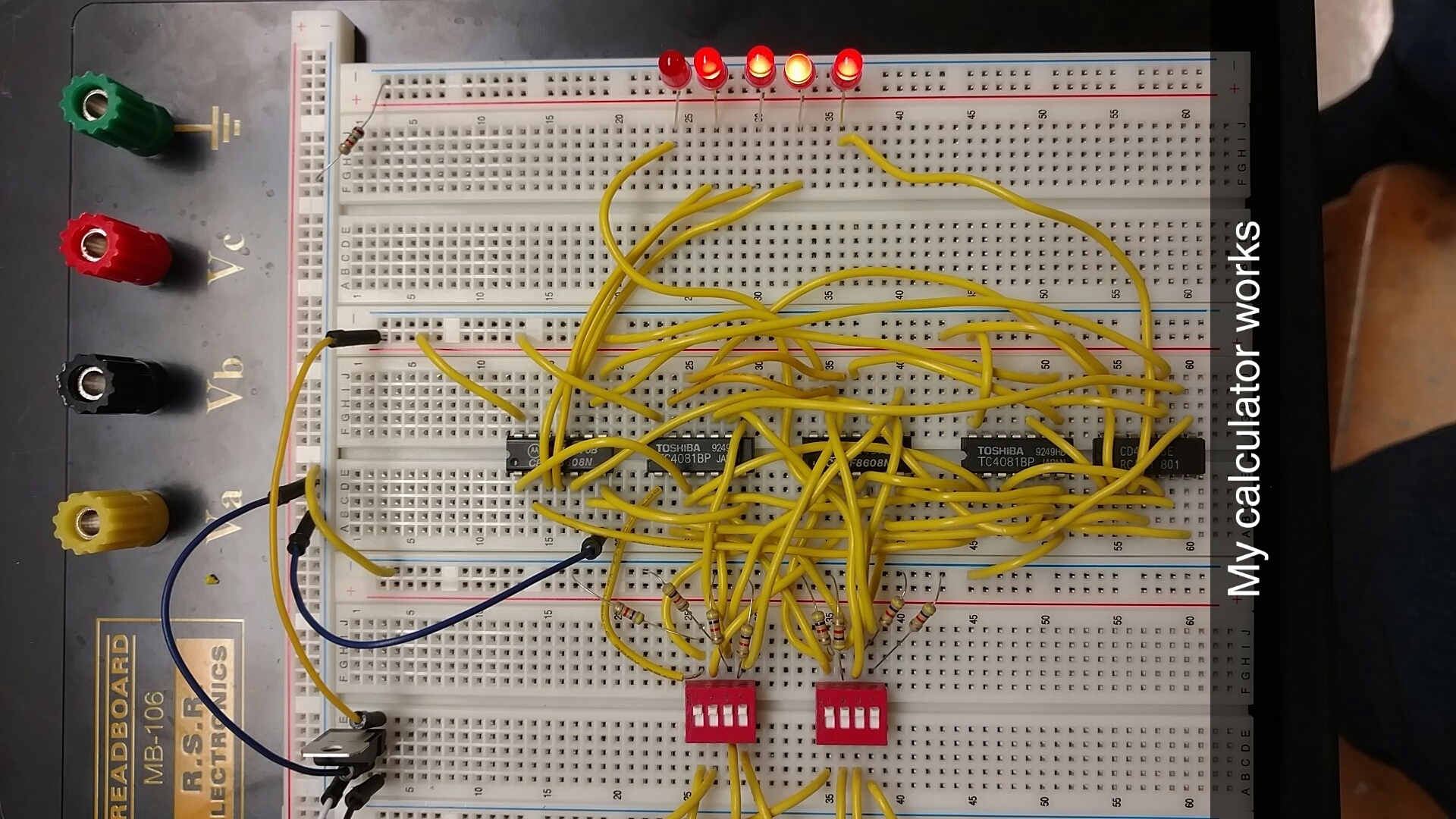 Photo of the 4 bit adder prototyped on a breadboard, a mess of yellow jumper wires are used.
